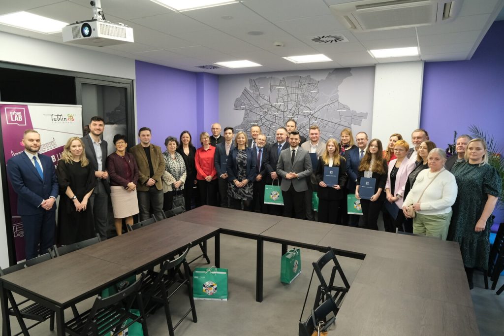 Grupa ludzi pozujących do zdjęcia. W rękach trzymają dyplomy i nagrody.