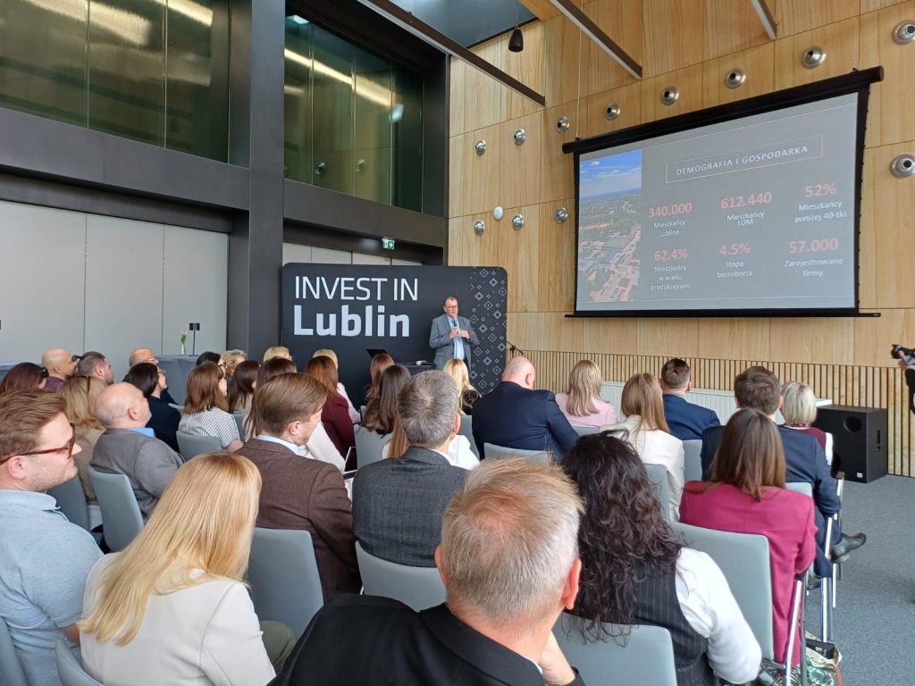 Sala konferencyjna pełna ludzi. W tle prezentacja o Lublinie.
